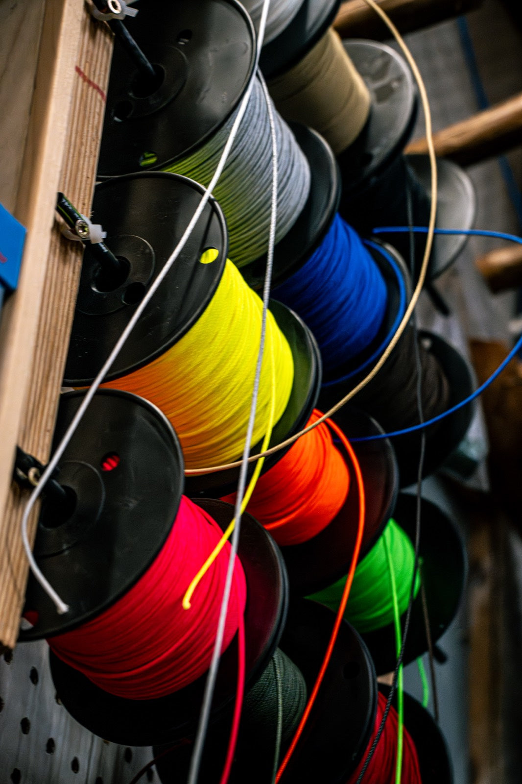 Rack of bowstring and serving spools in every color on a shop wall